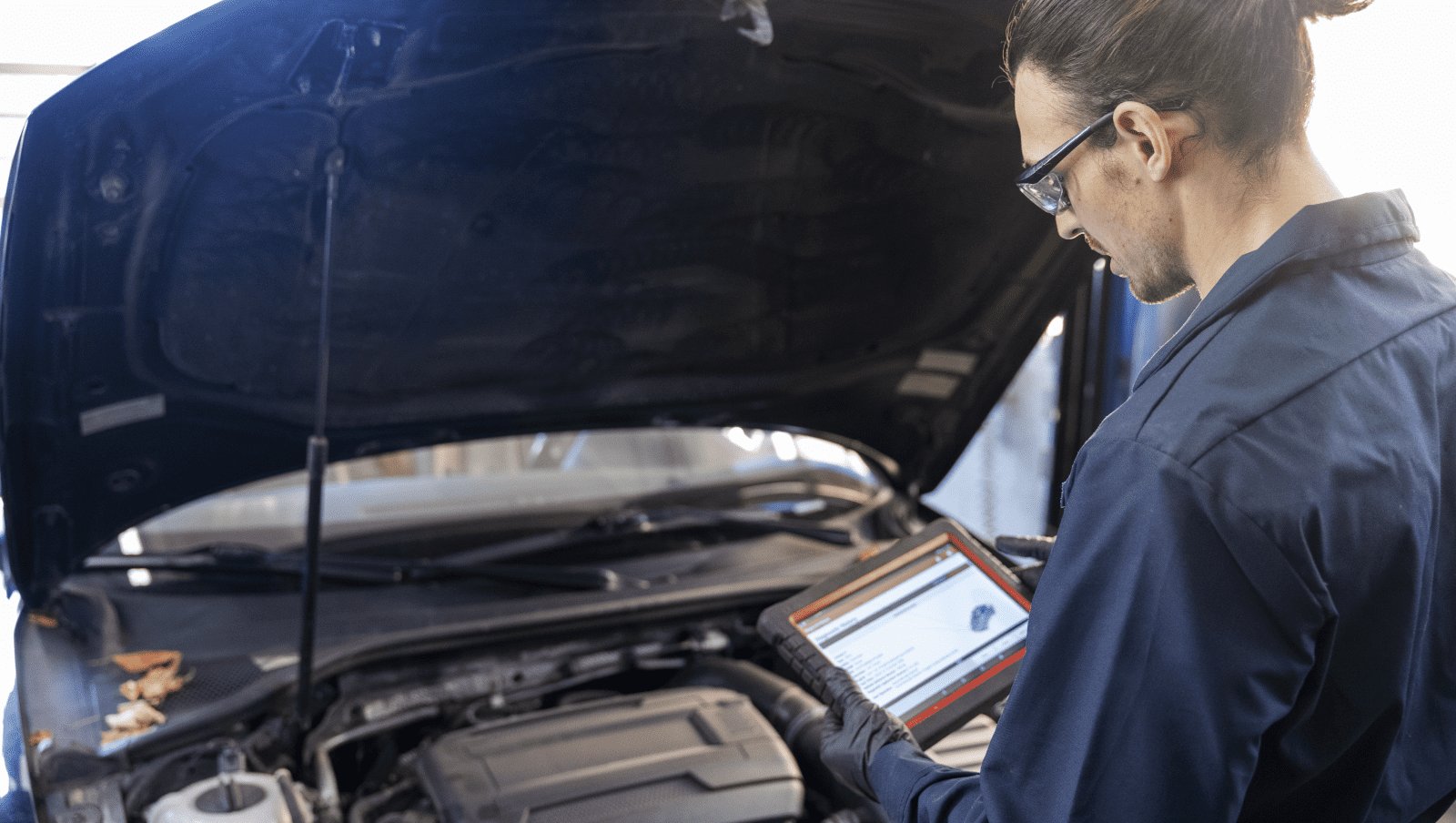 Mécanicien automobile inspectant un véhicule avec une tablette électronique