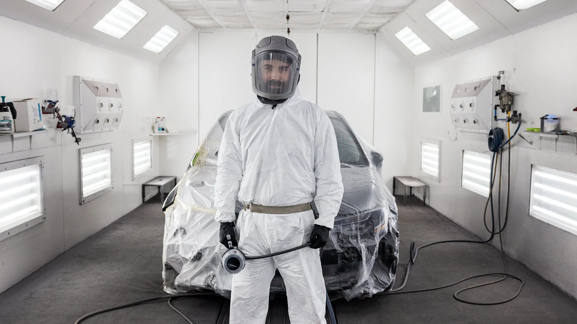 Peintre automobile dans un atelier blanc devant une voiture